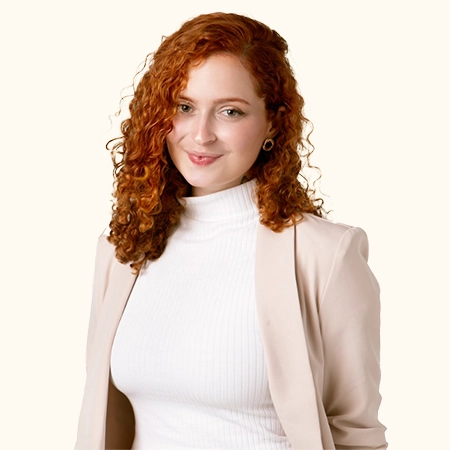 foto da psicóloga Larissa, sorrindo, usando uma camisa de gola rolê branca e um blazer bege